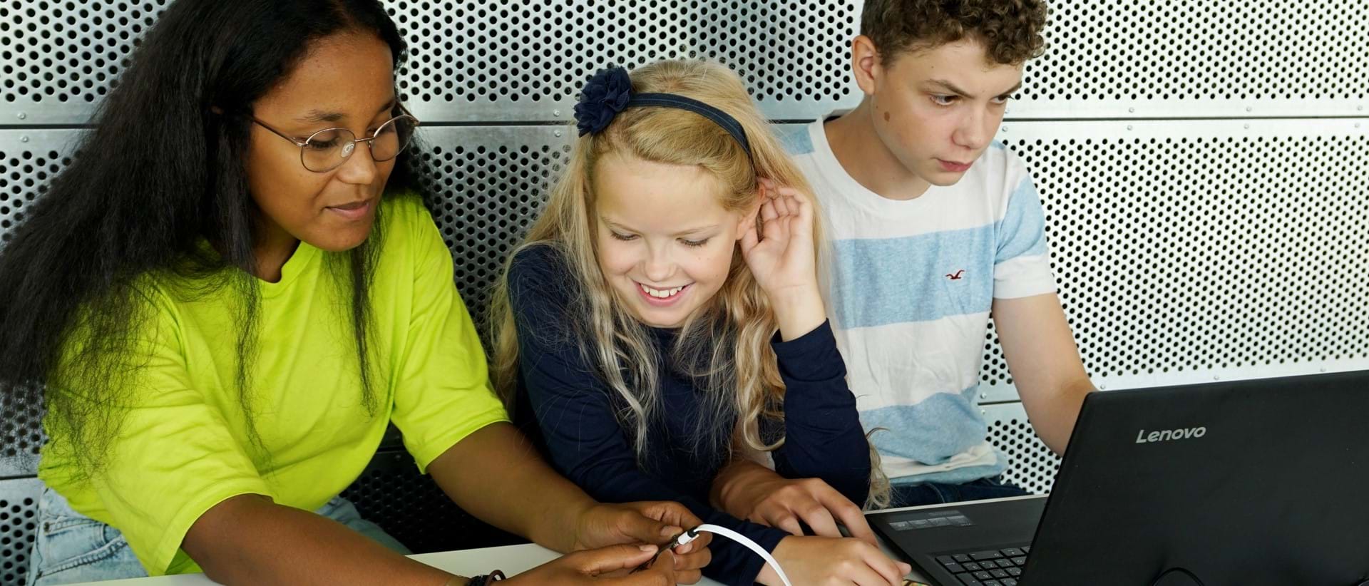 Tre elever sitter foran datamaskin og jobber med en micro:bit