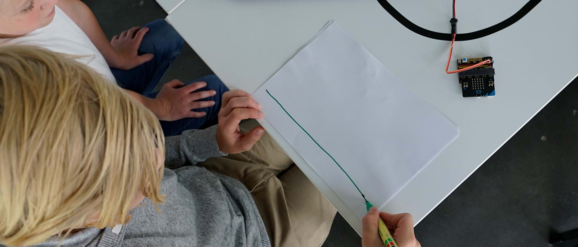 Gutt tegner en vannrett strek på hvitt ark